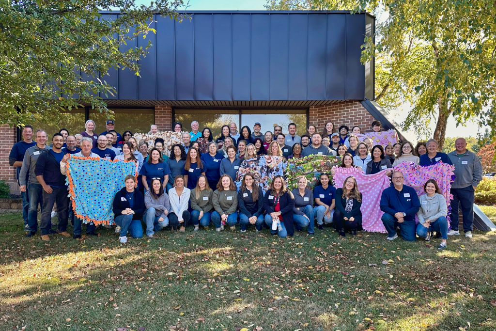 Highland Bank staff standing outside holding blankets they made to donate